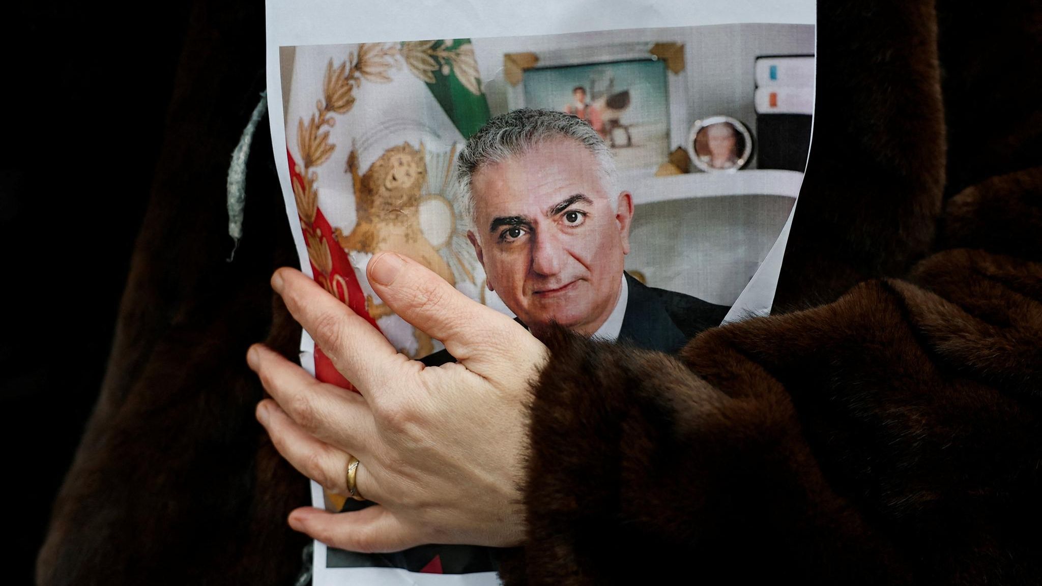 Eine Frau hält ein Bild von Reza Pahlavi im Arm
