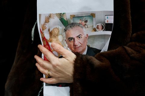 Eine Frau hält ein Bild von Reza Pahlavi im Arm