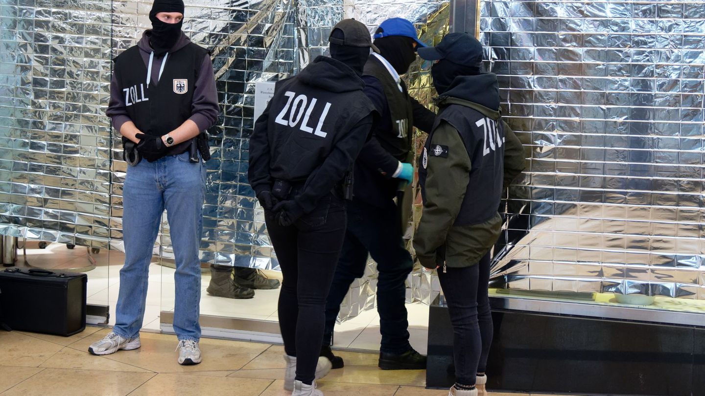 Zollbeamte stehen vor einem Nagelstudio in der Neumarktgalerie in der Innenstadt von Köln. Foto: Henning Kaiser/dpa