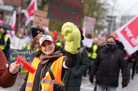 Eine Teilnehmerin der Kundgebung reckt einen übergroßen Handschuh in die Höhe. Foto: Marcus Brandt/dpa