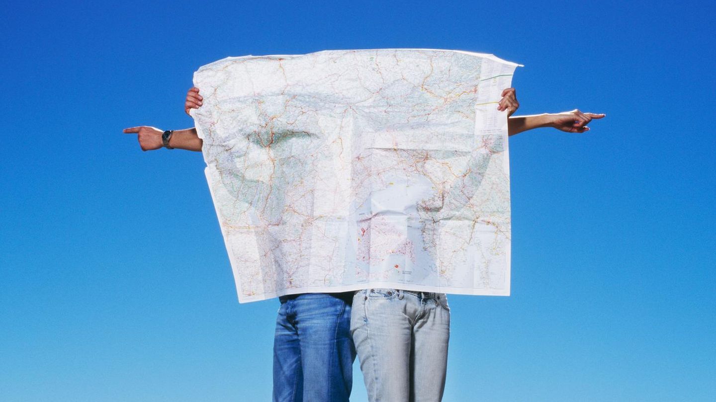 Gen Z Zwei Menschen verbergen sich hinter einer großen Landkarte, sie deuten in unterschiedliche Richtungen