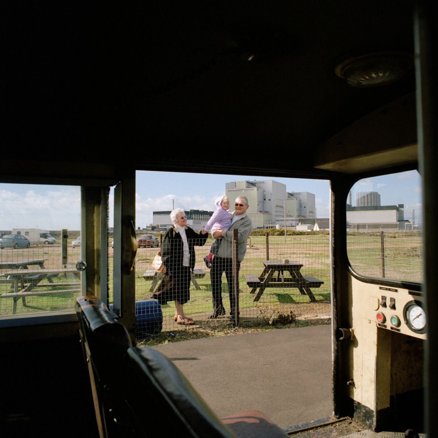 Der Blick aus einem Zugabteil zeit wie zwei ältere Personen mit einem Kleinkind vor einem Zaun stehen