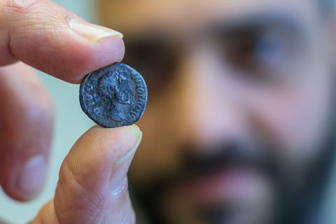 Ein Mitarbeiter des Landesamtes für Denkmalpflege und Archäologie präsentiert eine römische Münze aus dem frühen 3. Jahrhundert