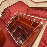 Treppenhaus von oben: Eingekleidet mit rot-schwarz gemustertem Teppich