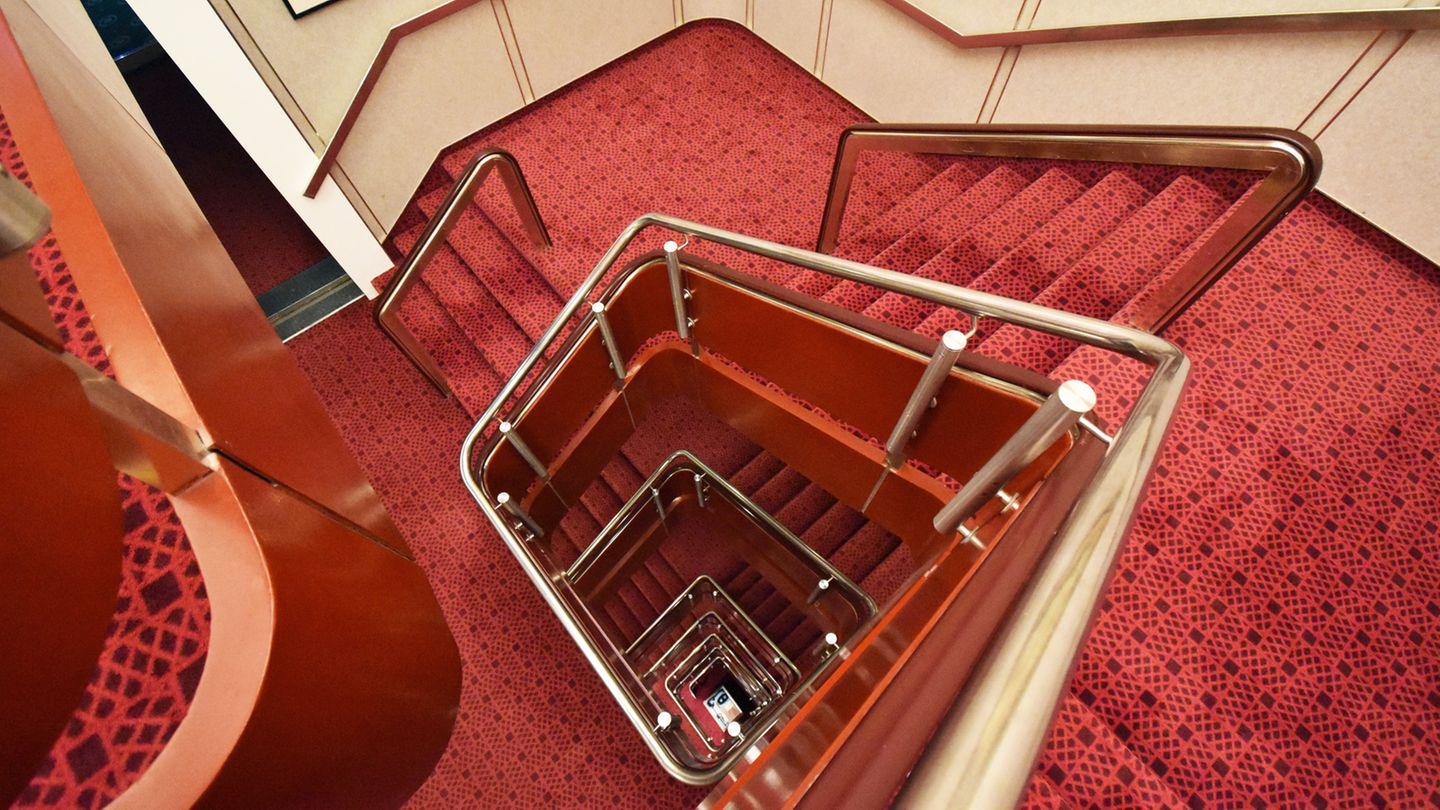 Treppenhaus von oben: Eingekleidet mit rot-schwarz gemustertem Teppich