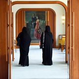 Zwei Frauen laufen durch hölzerne Flügeltüren auf ein deckenhohes Gemälde zu