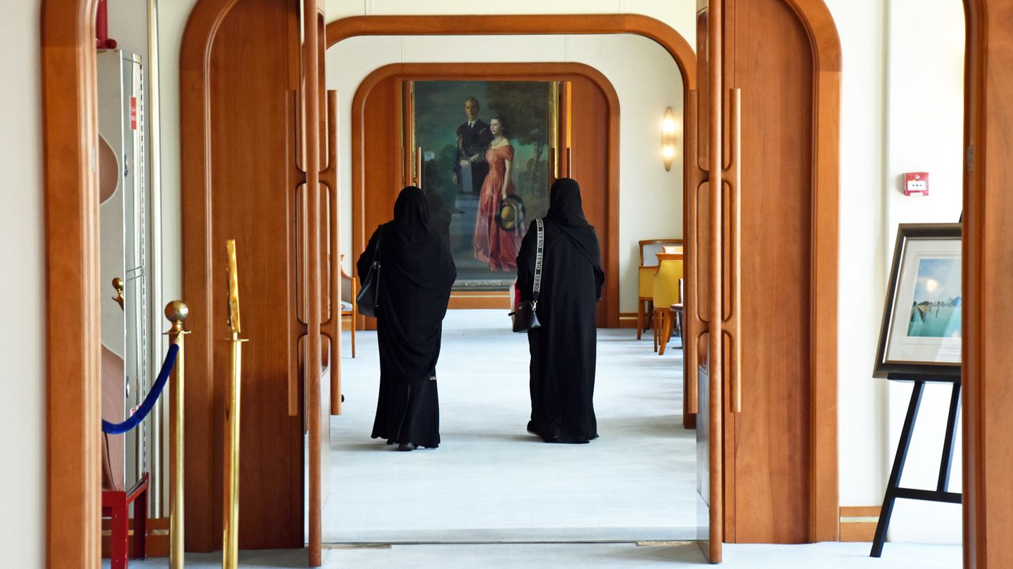 Zwei Frauen laufen durch hölzerne Flügeltüren auf ein deckenhohes Gemälde zu