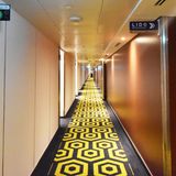 Ein großzügig beleuchteter Gang auf dem Kreuzfahrtschiff. Rechts zeigt ein Schild in Richtung Lido Restaurant