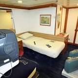 Einzelkabine auf dem Schiff QUE1, dekoriert von alten Koffern und einem Röhrenfernseher