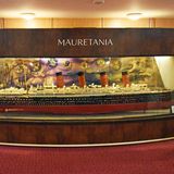 Ein Mann in traditionellem, langem weißen Gewand betrachtet das Modell-Schiff