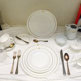 Weiß-goldenes Porzellanservice, Kristallgläser und Messing-Besteck in der Ausstellung