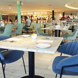 Modernes Restaurant "Lido" mit blauen Samtstühlen und marmorierten Bistrotischen