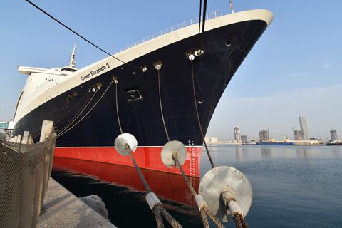 Die Qeen Elizabeth 2, ein schwarzes Schiff mit rotem Unterteil, im Hafen von Dubai