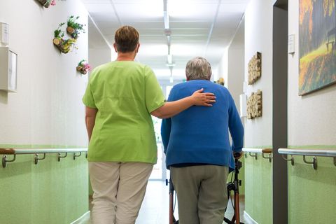 Eine Altenpflegerin geht mit einer Bewohnerin durch ein Seniorenheim (Archivbild)