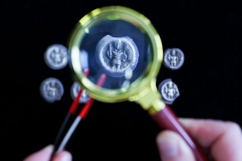 Mittelalterliche Silbermünzen aus dem 12. Jahrhundert unter einer Lupe. Foto: Jan Woitas/dpa