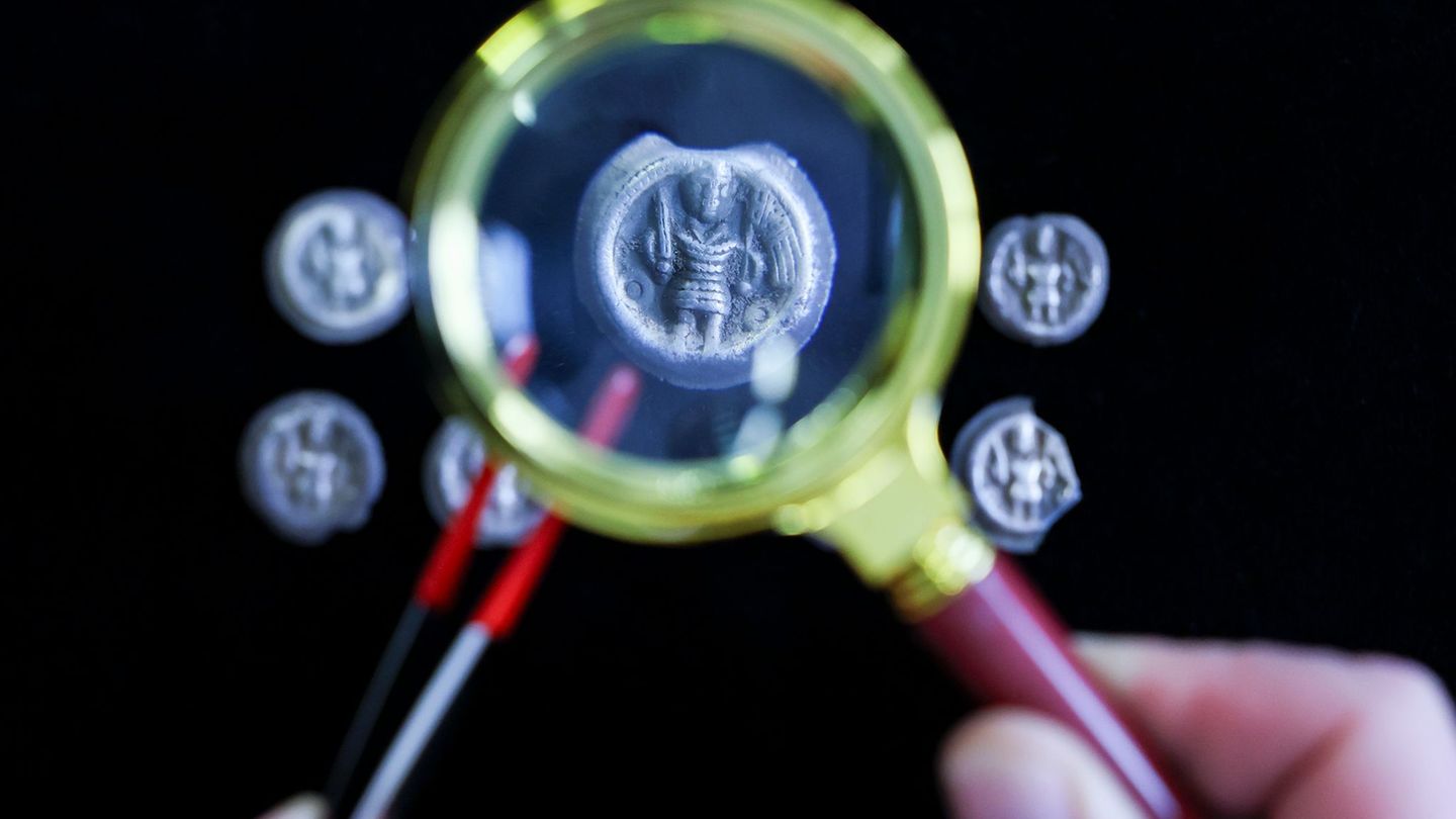 Mittelalterliche Silbermünzen aus dem 12. Jahrhundert unter einer Lupe. Foto: Jan Woitas/dpa