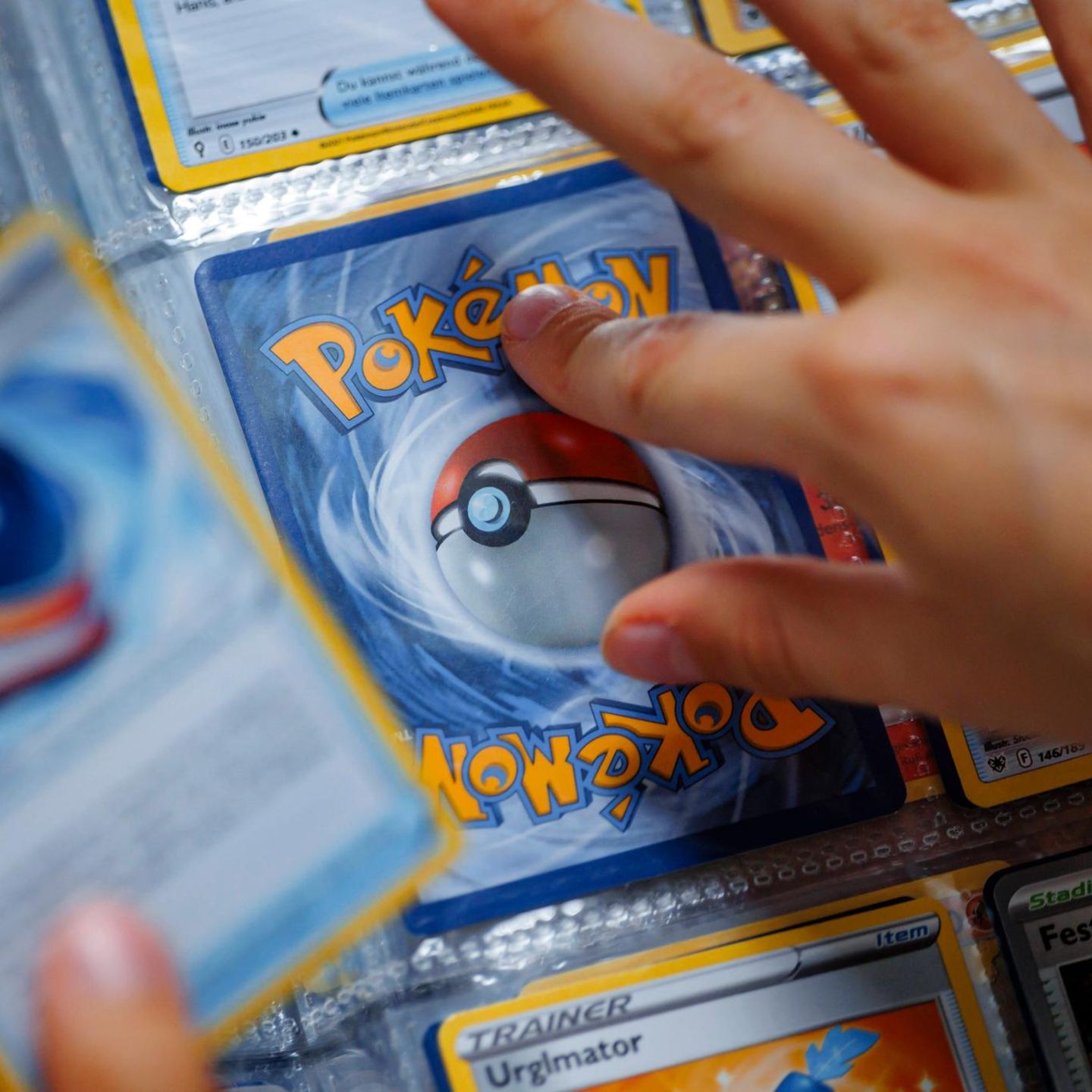 Eine Hand tippt auf eine Pokémon-Sammelkarte