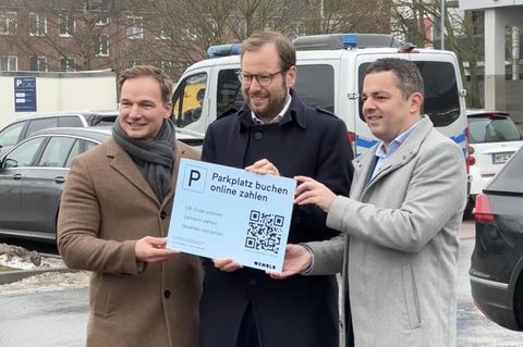 Drei Männer stehen auf einem Parkplatz