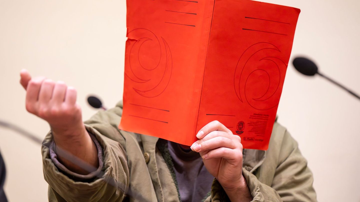 Der Angeklagte verdeckte sein Gesicht zum Prozessauftakt zunächst mit einer Mappe. Foto: Peter Kneffel/dpa