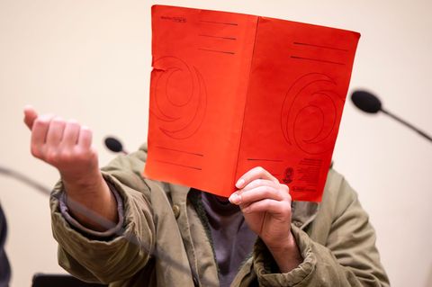 Der Angeklagte verdeckte sein Gesicht zum Prozessauftakt zunächst mit einer Mappe. Foto: Peter Kneffel/dpa