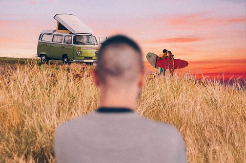 Ein Mann blickt auf ein küssendes Paar neben einem Van