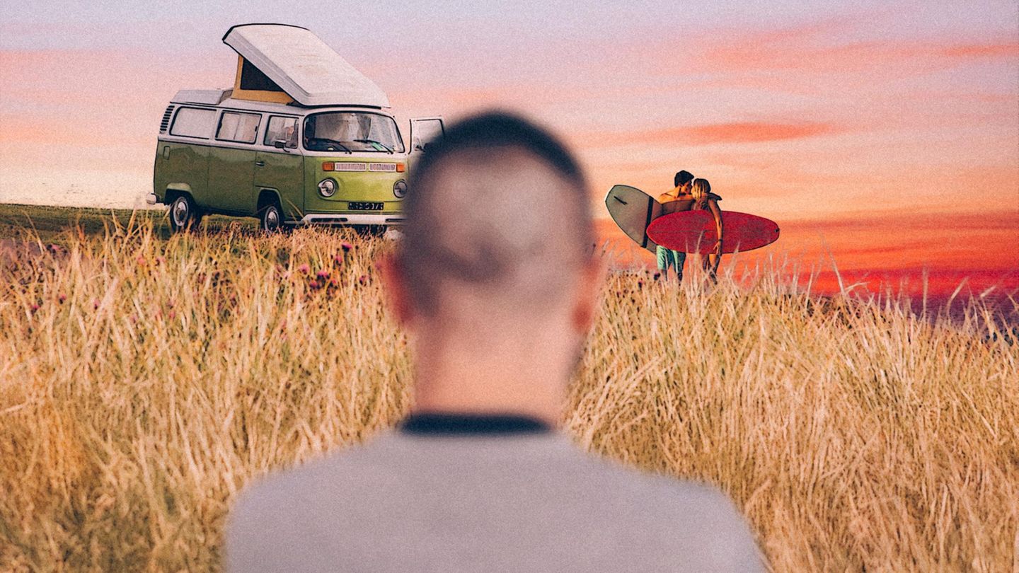 Ein Mann blickt auf ein küssendes Paar neben einem Van