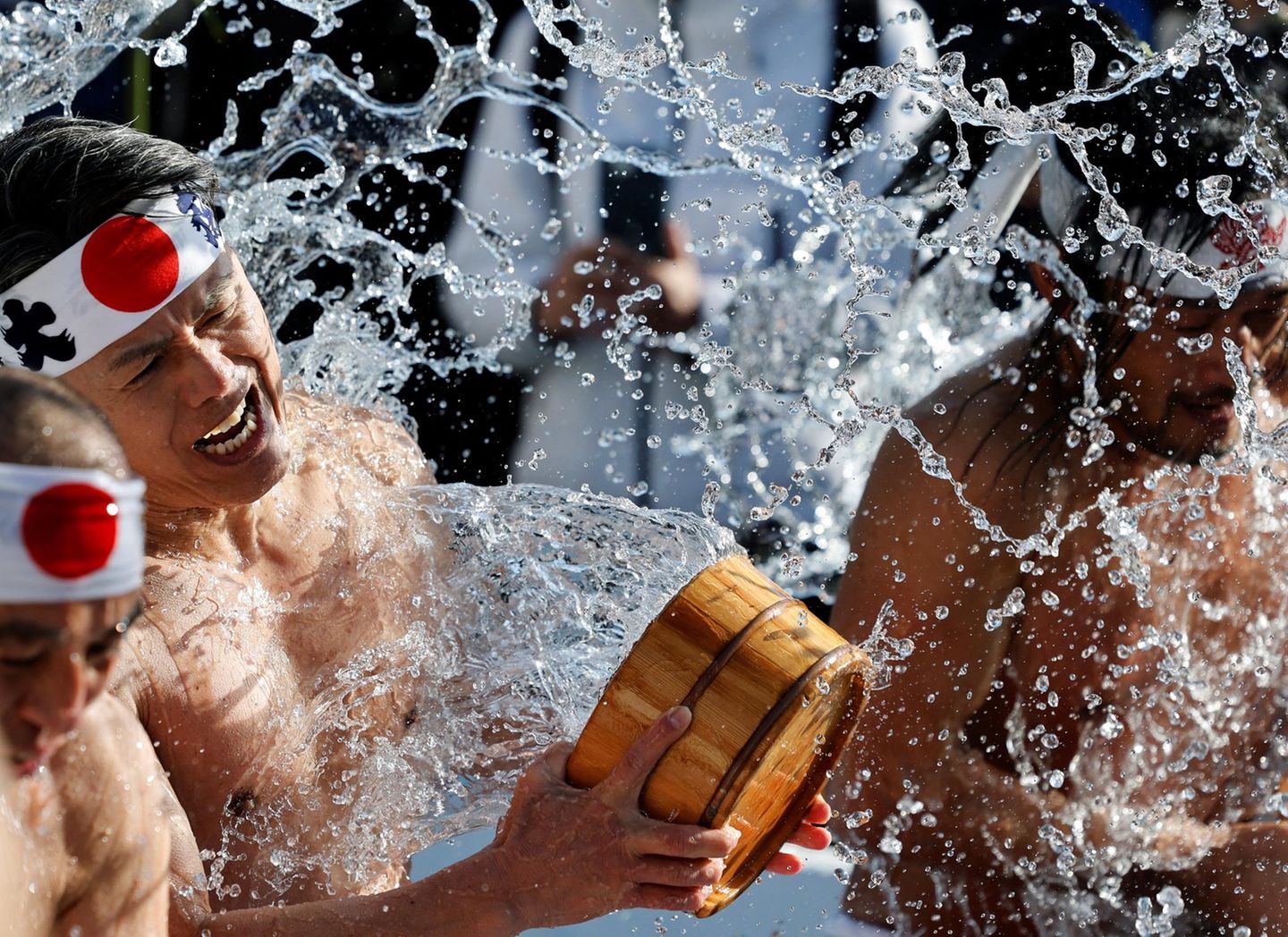 Tokio, Japan. Männer übergießen sich am Kanda-Myōjin-Schrein in Tokio mit eiskaltem Wasser, um beim jährlichen Kaltwasser-Ritual Körper und Geist zu reinigen. Die Zeremonie soll die Seele läutern, innere Stärke fördern und Glück sowie Gesundheit für das neue Jahr bringen. Das traditionelle Ritual zieht jedes Jahr zahlreiche Teilnehmer und Zuschauer an