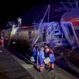 Rettungskräfte im Einsatz auf dem Dach von einem der Züge. Die Waggons sind massiv beschädigt