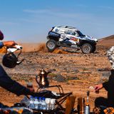 Zuschauer bereiten in Saudi-Arabien auf traditionelle Weise Tee zu, während im Hintergrund ein Rennwagen der Rallye Dakar Staub aufwirbelt. Der Wettbewerb hat eine lange Geschichte, hieß ursprünglich "Ralley Paris-Dakar", gastierte auch schon in Südamerika und wird inzwischen von Saudi-Arabien ausgerichtet. Wegen vieler Todesfälle, hoher Kosten und ökologischer Folgen steht die Veranstaltung seit Jahren in der Kritik