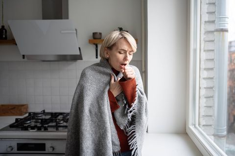 Husten: Frau hustet in der Küche