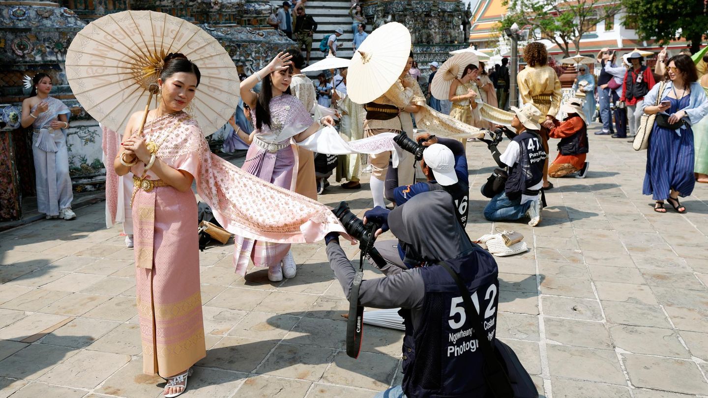 Bangkok, Thailand. Am Tempel Wat Arun posieren Touristinnen in traditonellen Gewändern für Fotos. Thailand hofft, 2026 wieder mehr Reisende anzulocken als 2025 – nämlich 36,7 statt 32,9 Milionen. Aber das schaffen die Damen in ihren Gewändern wohl nicht allein – trotz aller Anmut
