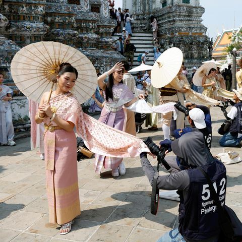 Bangkok, Thailand. Am Tempel Wat Arun posieren Touristinnen in traditonellen Gewändern für Fotos. Thailand hofft, 2026 wieder mehr Reisende anzulocken als 2025 – nämlich 36,7 statt 32,9 Milionen. Aber das schaffen die Damen in ihren Gewändern wohl nicht allein – trotz aller Anmut
