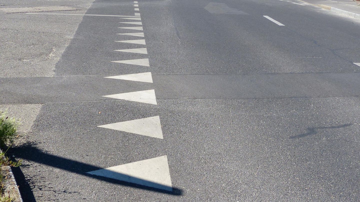 Verkehrszeichen: Eine Reihe aus weißen Dreiecken sind auf den Asphalt einer Straße gemalt.