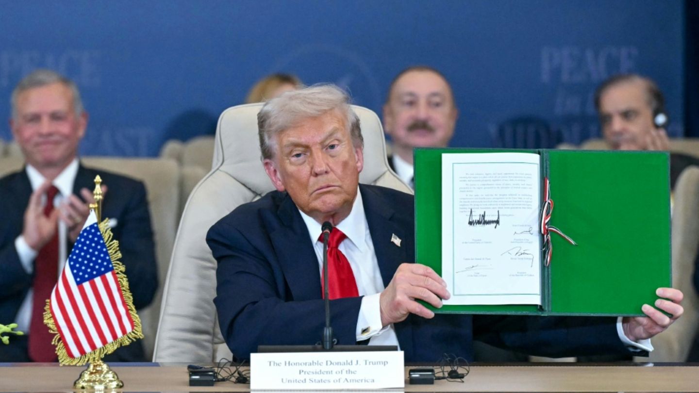 Trump hält ein unterschriebenes Dokument hoch
