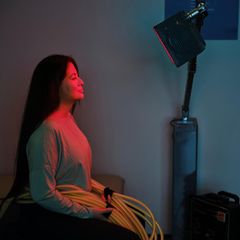 Deal News: Eine Frau sitzt vor einem Infrarotstrahler