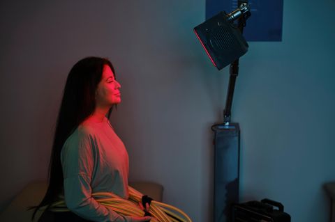 Deal News: Eine Frau sitzt vor einem Infrarotstrahler