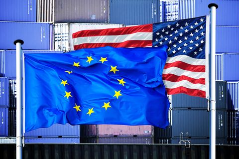 Zwei Flaggen wehen im Wind: eine EU-Flagge und eine USA-Flagge.