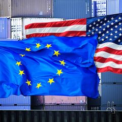 Zwei Flaggen wehen im Wind: eine EU-Flagge und eine USA-Flagge.