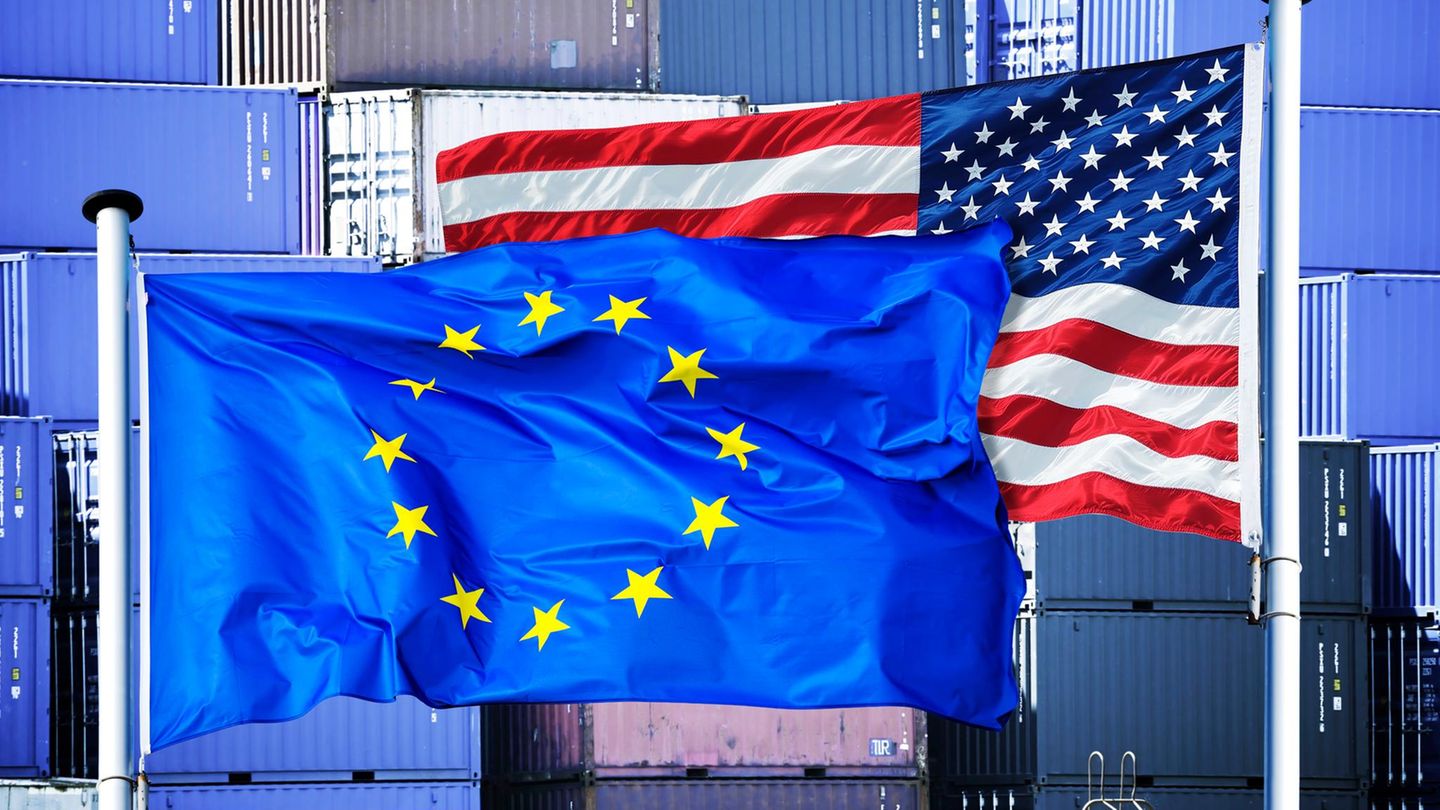 Zwei Flaggen wehen im Wind: eine EU-Flagge und eine USA-Flagge.