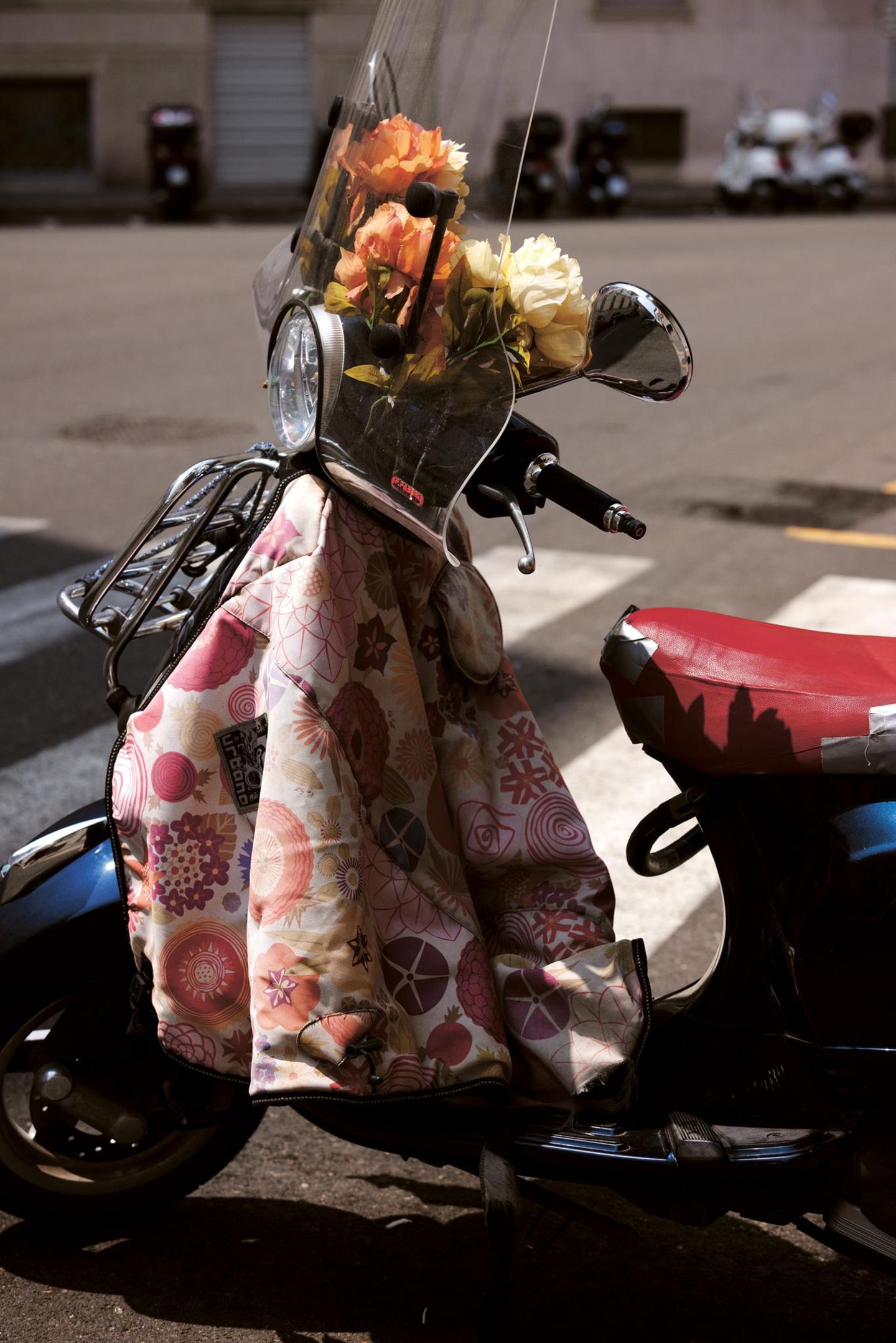 Ein Motorroller mit Blumen und einer Jacke am Lenker