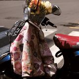 Ein Motorroller mit Blumen und einer Jacke am Lenker