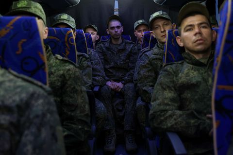 Soldaten aus Russland sitzen nach einem Gefangenenaustausch in einem Bus zurück in Richtung Heimat