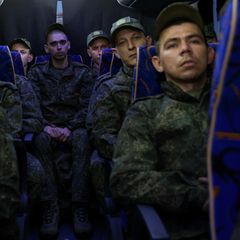 Soldaten aus Russland sitzen nach einem Gefangenenaustausch in einem Bus zurück in Richtung Heimat