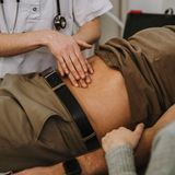 einem jungen Mann wird der Bauch abgetastet