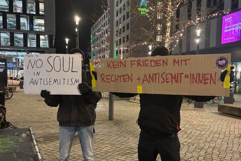 Zwei Demonstrierende halten vor der Uber-Arena in Berlin Plakate gegen Xavier Naidoo hoch