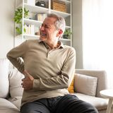 Ein Mann hält sich vor Schmerzen den Rücken