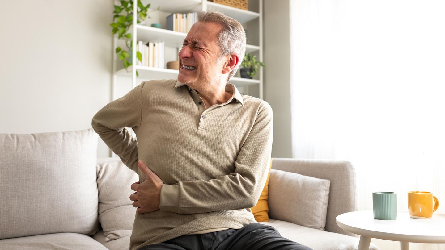 Ein Mann hält sich vor Schmerzen den Rücken