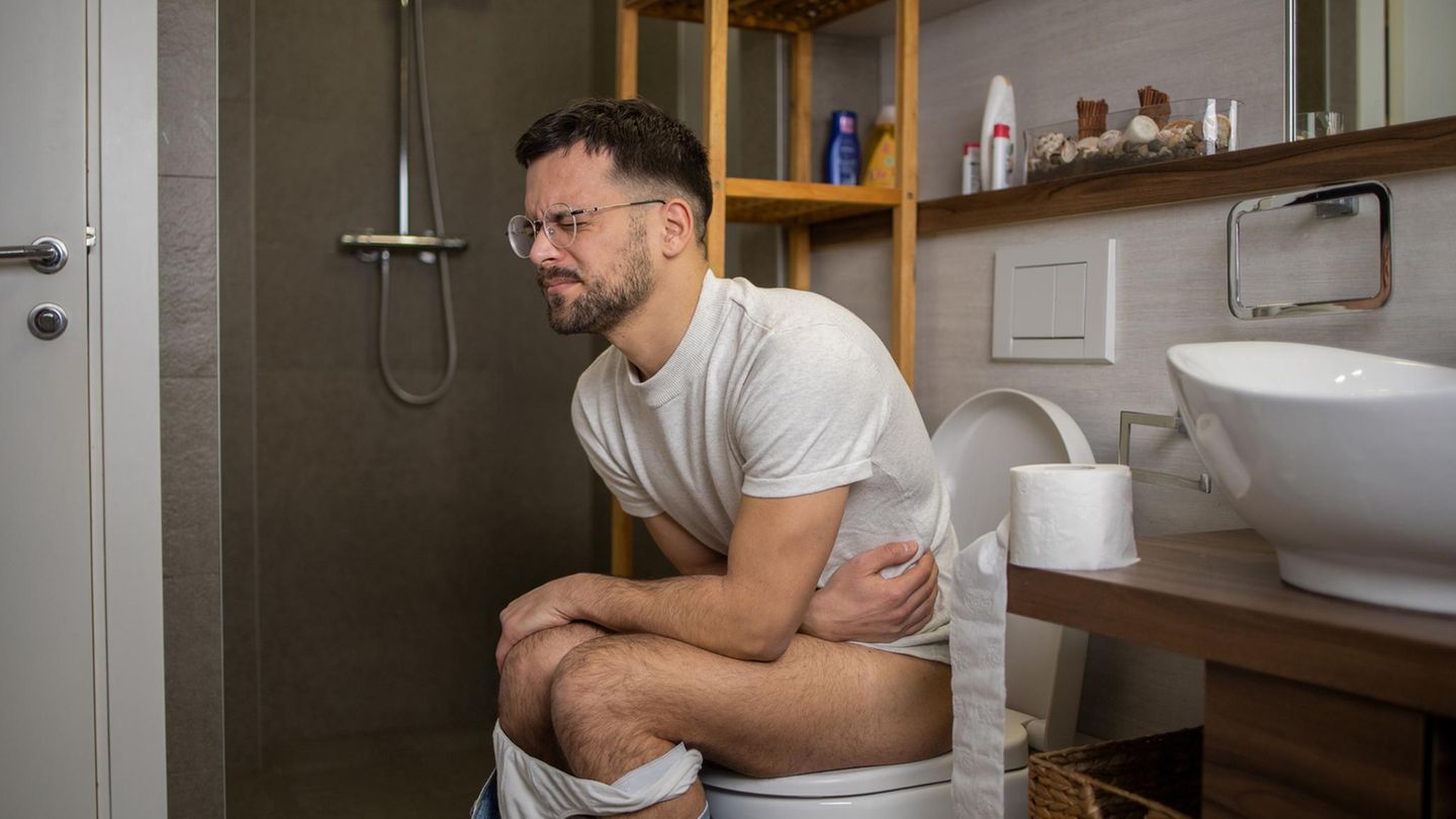 Ein Mann sitzt auf Toilette und presst