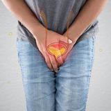 Ein Mann fasst sich verkrampft in den Schritt