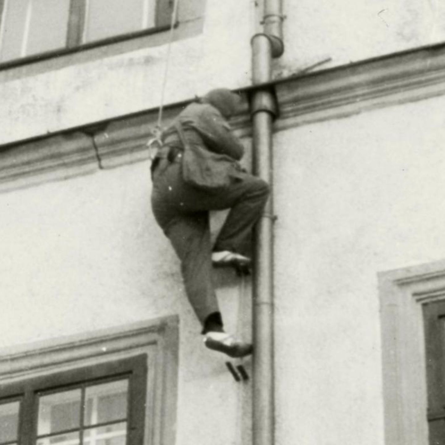Ein Mann klettert an einer Regenrinne eine Hauswand hoch